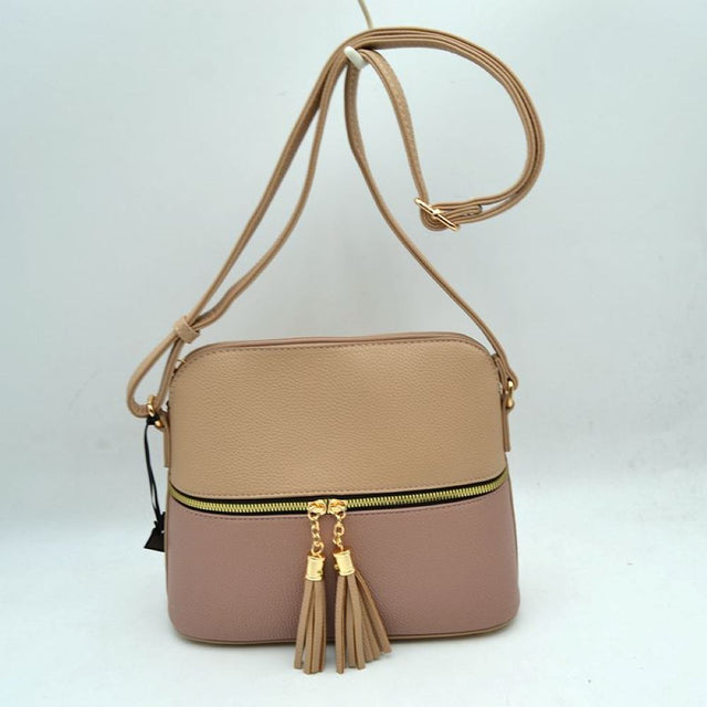 Beige This everyday crossbody bag features a structured pebbled texture body with a distinct two-toned paneled design. Ideal for organized daily use, it showcases a prominent horizontal front zipper with dual gold-toned pulls, each adorned with a decorative hanging fringe tassel. The main storage compartment is paired with a matching long