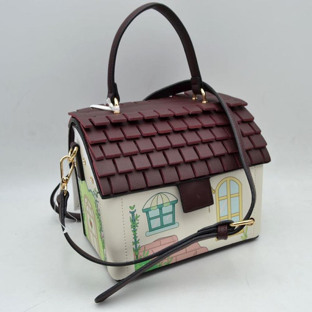 Beige Add a touch of playful charm to your accessory collection with this uniquely designed handbag, . Shaped like a cozy cottage, this structured bag features a dimensional tiered roof design that doubles as the main flap closure. The front showcases a delightful, illustrated house exterior complete with a window, door, and garden accents. Engineered for versatility, it comes equipped with a sturdy top handle and an adjustable, removable shoulder strap for effortless crossbody or over-the-shoulder wear.