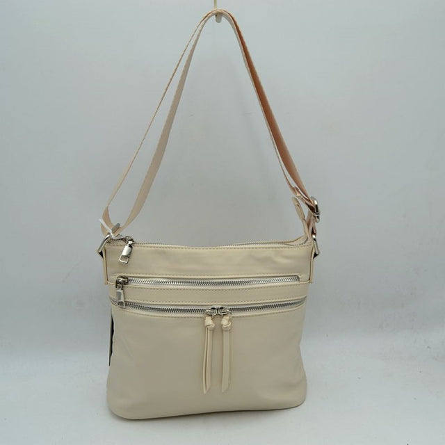 Beige This functional shoulder bag features a smooth, streamlined exterior designed with multiple exterior storage compartments for convenient everyday use. The front panel includes a top zippered pocket with a classic metal pull and a lower zippered pocket detailed with distinctive knotted dual pulls. A long, adjustable shoulder strap is attached securely to the sides with metal rings and a sleek adjustment buckle, allowing for comfortable over-the-shoulder or crossbody carrying.