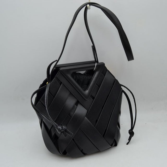 Black This structural bucket bag features a distinctive geometric design composed of overlapping wide woven straps that create an eye-catching pattern, making it a unique statement piece for everyday use. A rigid triangular cutout shape forms an integrated top handle, while an additional long, flat shoulder strap extends from the upper frame for comfortable over-the-shoulder carrying.