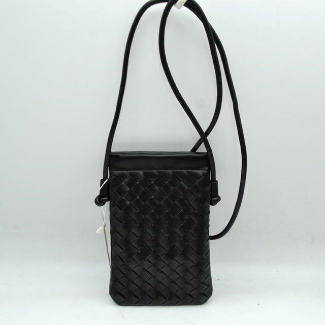 Black This compact vertical crossbody bag is designed for everyday functionality with a distinct woven textured pattern across its body. It features a slim, continuous cord strap attached securely to the sides with visible knot details for comfortable carrying. A clean horizontal opening at the top allows effortless access to the main storage compartment