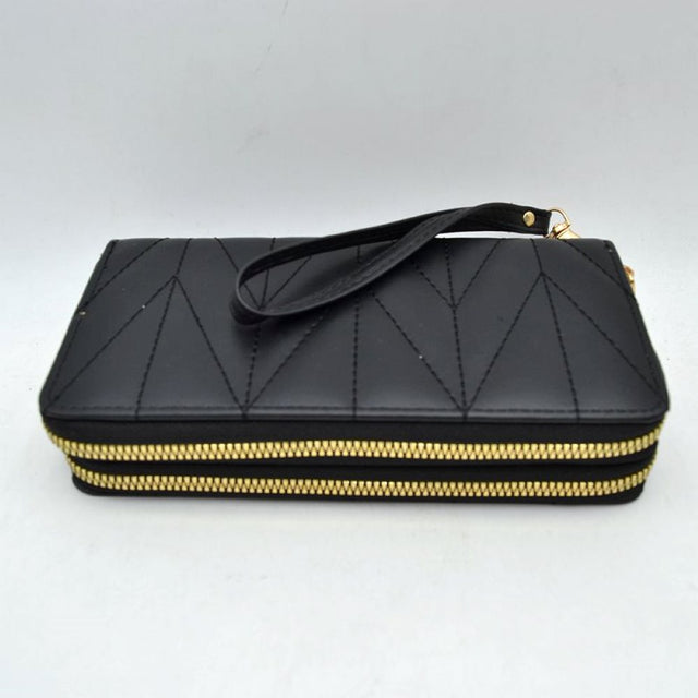 Black This rectangular long wallet features a distinctive geometric stitched pattern across its exterior, providing a refined and structured look for everyday use. Designed to offer organized storage compartments, it incorporates a dual zip-around closure system with prominent metallic zippers to keep essentials secure. A matching, detachable flat wristlet strap is connected to the side hardware with a metallic clasp, providing an easy and convenient hands-free carrying style.