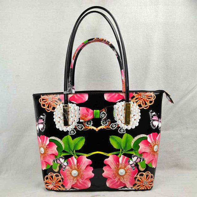 Black This eye-catching tote bag features a vibrant, high-gloss finish with a striking print of large pink blossoms, green leaves, butterflies, and rhinestone-style details set against a sleek black patent background. The front is charmingly accented with a printed bow and faux-pearl cluster motif, adding a playful touch of elegance. Designed with a structured, spacious silhouette, it features a secure top zipper closure to keep your essentials safe and is completed with slim