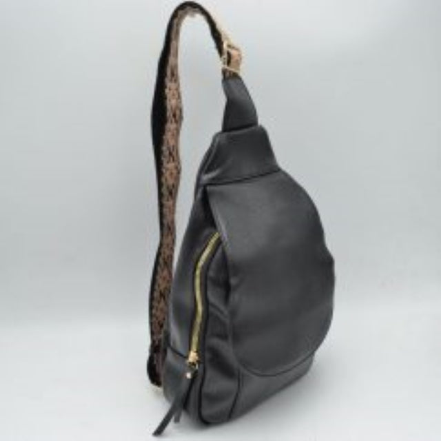 Black This functional sling bag features a teardrop silhouette designed for comfortable everyday use and hands-free convenience. It offers organized storage, including a main zippered compartment with metallic zipper hardware and pull tabs, complemented by a front flap closure section. The wide, adjustable shoulder strap showcases an intricate patterned weave and includes a metallic slide buckle for a customizable fit across the body.