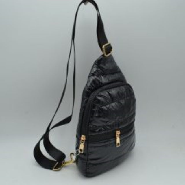 Black This functional sling backpack features a lightweight puffer exterior with horizontal quilted channels in a glossy classic black finish, making it a sleek choice for active daily use, travel, or commuting. Designed for convenient organization, it is equipped with a front horizontal zipper pocket for quick access to smaller items alongside a spacious main compartment with a secure curved zipper closure. Complete with eye-catching gold-tone hardware
