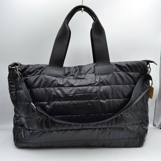 Black Upgrade your travel gear with this exceptionally spacious, lightweight weekender duffel bag, perfect for overnight trips, gym sessions, or casual weekend getaways. Featuring a stylish horizontally quilted puffer design, this bag combines a cozy, modern aesthetic with highly practical function. It is designed with wide, durable webbed top handles for a comfortable grip, alongside a matching adjustable and detachable shoulder strap secured by polished metallic clasps for easy hands-free carrying.