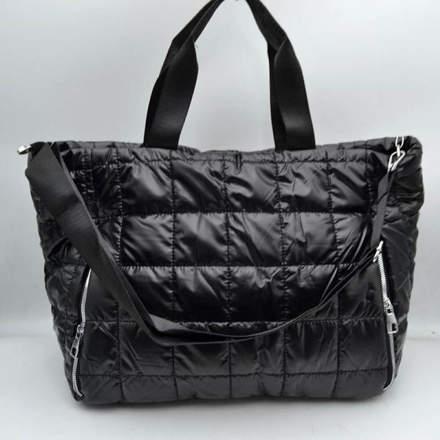 Black Simplify your travel routine with this highly functional, lightweight grid-quilted puffer duffel bag, perfectly proportioned for overnight stays, weekend road trips, or gym days. Featuring a contemporary square quilted design, this soft-structured bag brings an athletic yet polished aesthetic to your transit style. The exterior features two prominent vertical zippered pockets on the lower front corners, keeping your passport, keys, or phone easily accessible while on the move.