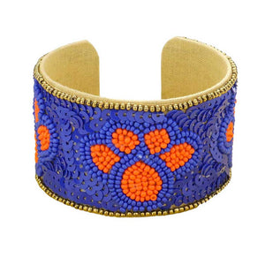 Blue Orange This stylish Game Day Sequin Seed Beaded Paw Accented Cuff Bracelet is the perfect way to show your team spirit. Crafted with sparkling sequins and beads, this bracelet features an eye-catching paw accent, perfect for any sports fan. Show your true allegiance on game day with this fashionable and unique accessory.