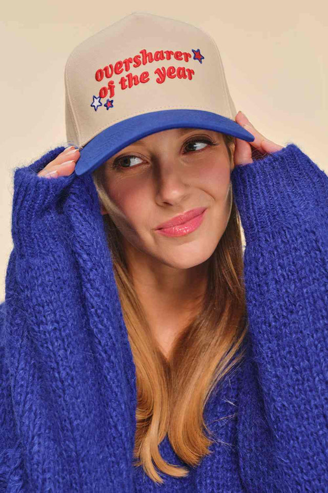 Blue Classic trucker style meets playful attitude with this C.C OVERSHARER OF THE YEAR snapback cap. Crafted from 100% cotton for breathable comfort, this two-tone baseball cap features embroidered lettering and star details that make a statement. The adjustable snap back closure fits one size, with a 22.5" circumference for a secure, comfortable fit. Perfect for casual wear or adding personality to any outfit.&nbsp;