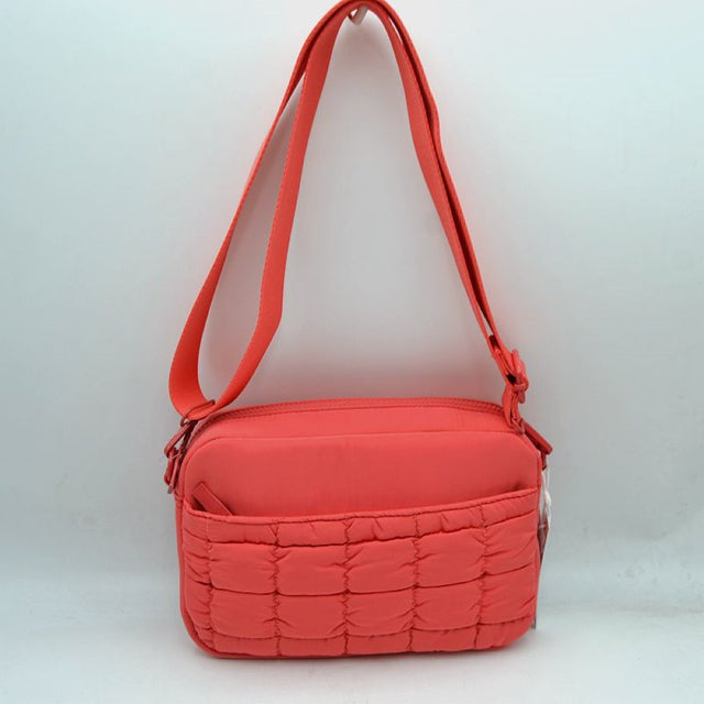 Coral This practical crossbody bag is designed for effortless everyday use, featuring a distinct quilted pattern across the lower front section. It offers multiple storage compartments, including a secure main zippered closure and an easily accessible front slip pocket to organize your daily essentials. A wide, adjustable shoulder strap ensures comfortable, customizable carrying, making it a perfect accessory for hands-free convenience while on the go.