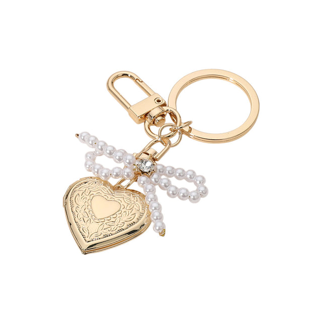 Cream Gold Pearl Beaded Bow Pointe Metal Heart Locket Bag Charm adds a touch of elegance to any bag. The pearl beads and metal heart locket create a stunning, timeless look. Perfect for adding a subtle pop of glamour to your everyday bag.