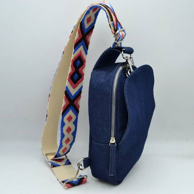 Dark Denim This functional sling bag features a structured silhouette with multiple storage compartments, including a secure zippered main section and an integrated front pocket for easy access to essentials. Perfect for everyday hands-free use, the bag is equipped with a wide, adjustable shoulder strap showcasing an intricate geometric woven pattern. Durable metal hardware and secure clasps connect the strap to the body of the bag, combining practical utility with a casual, modern design.