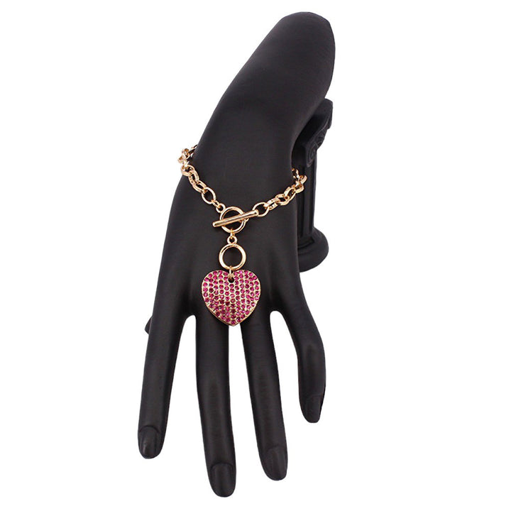 Fuchsia Stone Paved Heart Pendant Metal Toggle Bracelet, is a must-have accessory for any fashion-forward individual. Exquisitely crafted to elevate any outfit, this bracelet is a unique addition to your jewelry collection. Its toggle closure ensures a secure fit and its elegant style will make you stand out from the crowd.