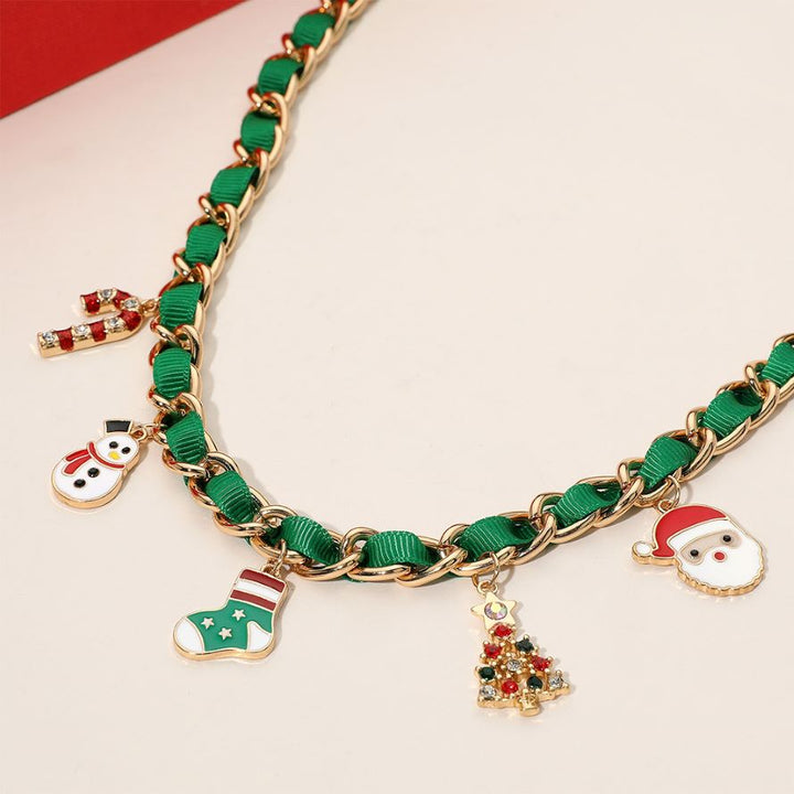 Holiday-themed necklace with enamel charms including a snowman, stocking, candy cane, Christmas tree, and Santa. Gold-tone chain interwoven with ribbon adds festive style. Made of iron, ribbon, and enamel.