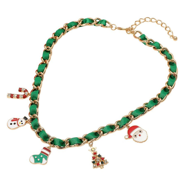 Holiday-themed necklace with enamel charms including a snowman, stocking, candy cane, Christmas tree, and Santa. Gold-tone chain interwoven with ribbon adds festive style. Made of iron, ribbon, and enamel.