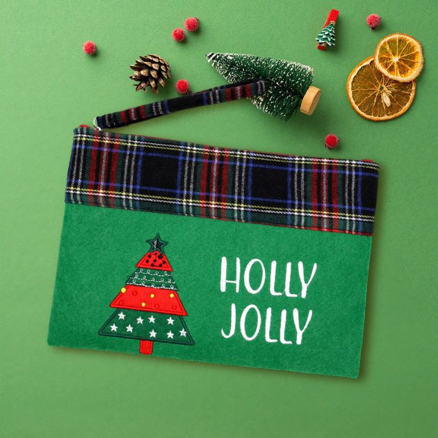 Add a touch of holiday joy with this “HOLLY JOLLY” pouch, featuring a festive Christmas tree and plaid trim. Perfect for holding small gifts, cosmetics, or travel items during the season. A merry little essential to keep your holiday organized and cheerful.
