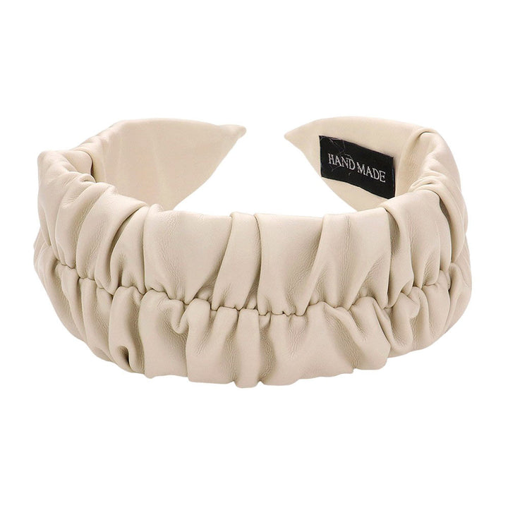 Ivory Pleated Solid Faux Leather Headband, This stylish accessory adds an elegant touch to any outfit. Made with high-quality materials, it is both comfortable and durable. The pleated design offers a unique, sophisticated look, while the faux leather adds a touch of luxury. Perfect for any formal or casual occasion wear.