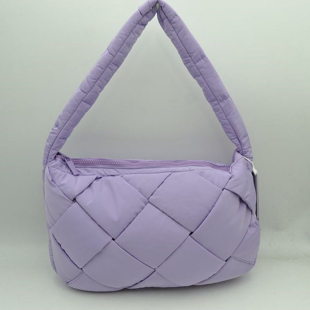 Lavender This padded shoulder bag features a distinctive interwoven design consisting of large, puffy square panels across the exterior. Ideal for effortless everyday use, it includes a wide, cushioned top strap integrated seamlessly into the sides for comfortable carrying. A matching top zipper closure runs along the upper edge to securely seal the main storage compartment while providing quick and easy access to essentials.