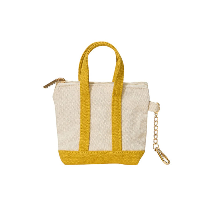Mustard Mini Canvas Pouch Bag doubles as a chic bag charm, combining style with practicality. Crafted from durable canvas, it offers a compact space perfect for carrying essentials like keys, cards, or small cosmetics. Its lightweight design attaches easily to your handbag, adding a trendy accent while keeping your valuables within reach. Ideal for those who value convenience and a polished look in everyday accessories.