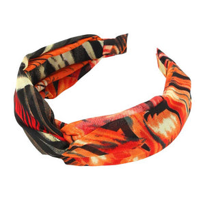 Orange Tropical Leaf Patterned Twisted Headband, perfect for adding a touch of summer to any outfit. Crafted with a unique twisted design and featuring a vibrant tropical leaf pattern, this headband is both stylish and functional. Stay on-trend and keep your hair in place with this fashionable accessory.