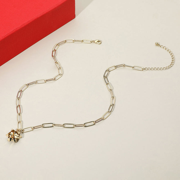 Trendy chain link necklace featuring a playful gift bow charm. A bold yet charming accessory that adds a modern edge and festive flair to casual or dressed-up outfits.