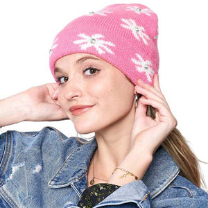 Pink Gem Flower Beanie Hat, Stay warm and fashionable with this. This knitted beanie features an intricate flower design with gems embedded in each petal, adding a glamorous sparkle to any outfit. The classic ribbed-knit construction ensures a snug fit for the perfect cold-weather accessory.
