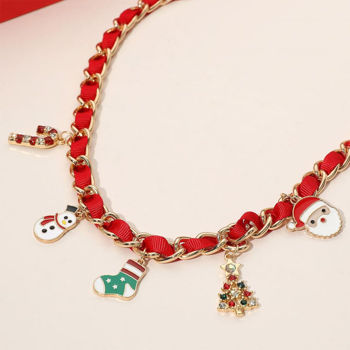Holiday-themed necklace with enamel charms including a snowman, stocking, candy cane, Christmas tree, and Santa. Gold-tone chain interwoven with ribbon adds festive style. Made of iron, ribbon, and enamel.