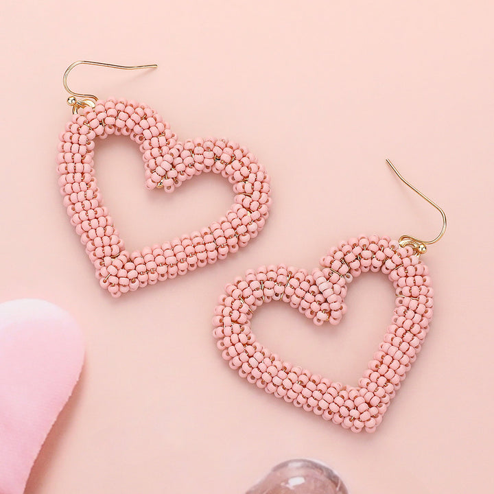 Seed Beaded Open Heart Dangle Earrings are handcrafted with delicate beads, forming an open heart that dangles elegantly. The intricate design adds a touch of romance to any outfit. These earrings are versatile and can be worn for any occasion, perfect for any fashion-forward individual. 