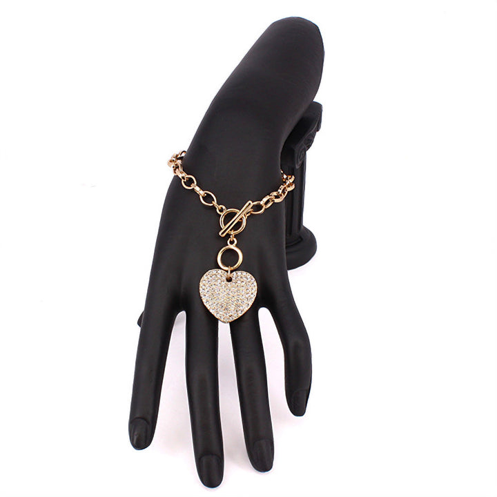 Stone Paved Heart Pendant Metal Toggle Bracelet is expertly crafted with a beautiful stone paved heart pendant and a durable metal toggle closure. The perfect accessory for any occasion, adding a touch of elegance and style to any outfit. Experience its timeless charm and versatility today.