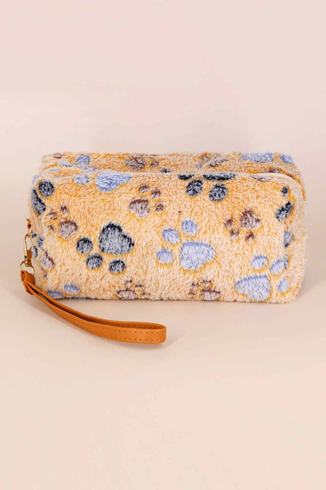 Adorable faux fur wristlet featuring playful paw print details. This compact pouch is perfect for carrying essentials like cards, cash, and small accessories on the go. Soft, plush texture with a convenient wrist strap for easy carrying. An ideal gift for animal lovers and a fun addition to any collection.